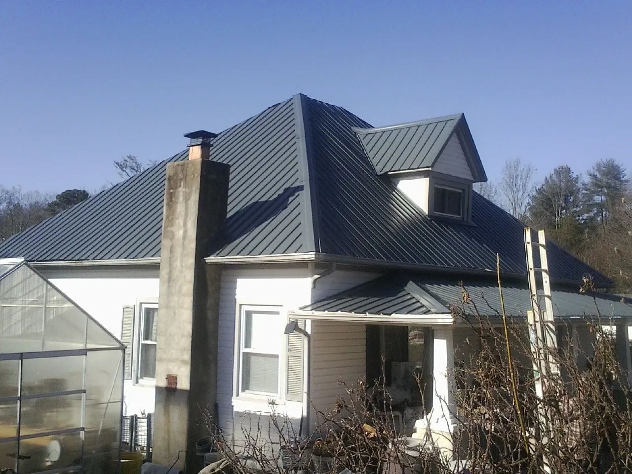 Dark blue standing seam metal roof on a white farmhouse with dormer — Slate & Tile Roof Repair by Roofing Brothers in Talbotton