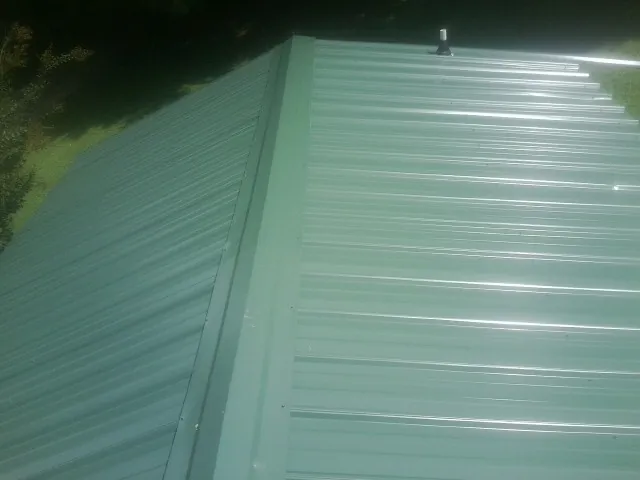 New green metal panels meeting at the ridge of a roof — Flat Roof Repair work by our crew in Talbotton