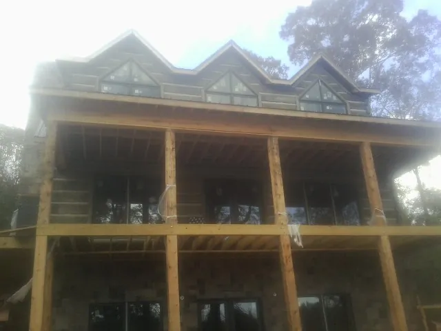 Dormers and porch framing on a large log home under construction — Roof Coating work by our crew in Talbotton