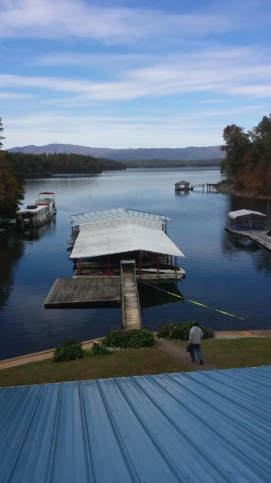 View across a lake from a newly installed blue metal roof in Talbotton