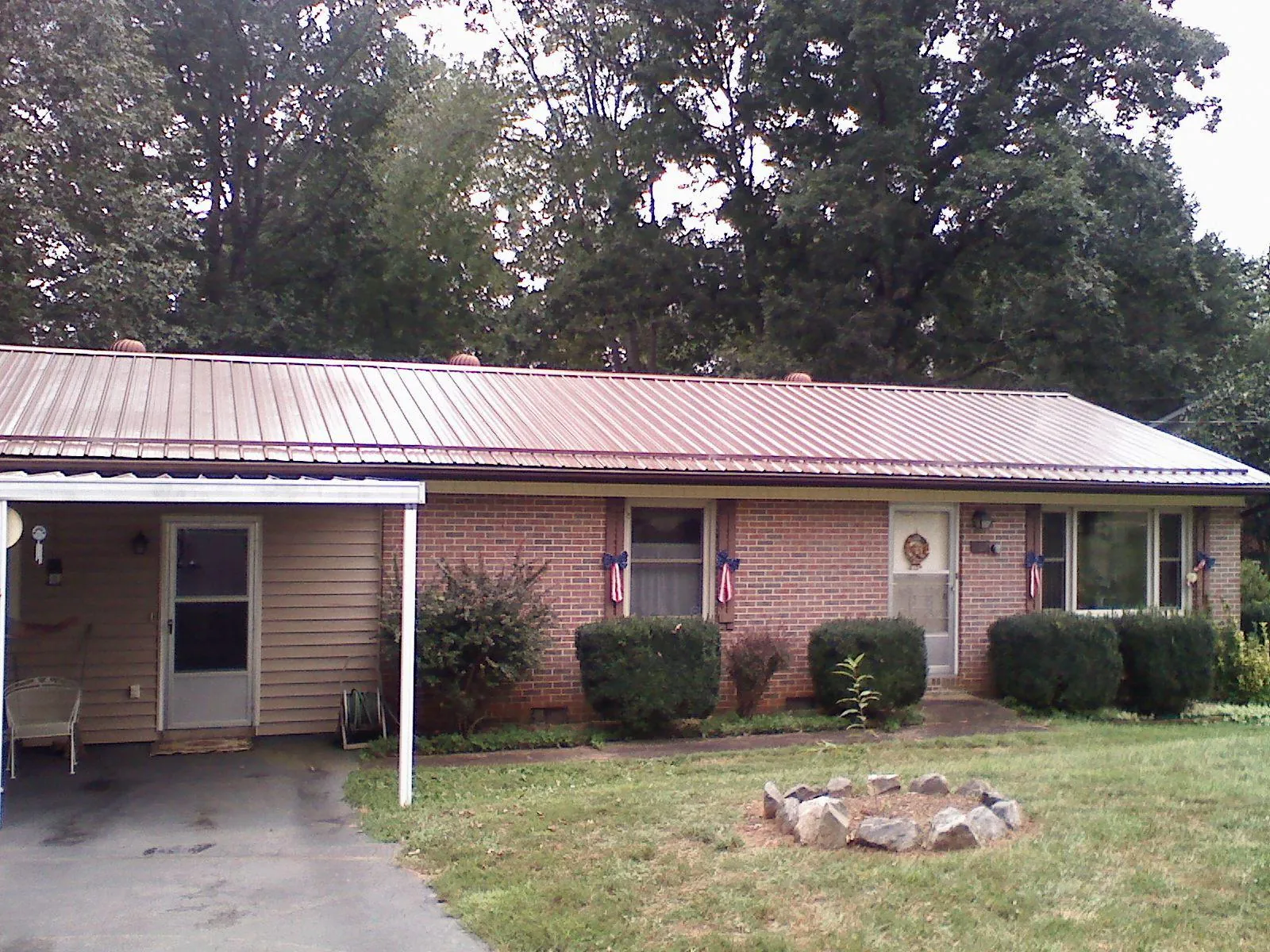 Bronze metal roof and carport on a brick ranch home — Roof Repair work by our crew in Talbotton