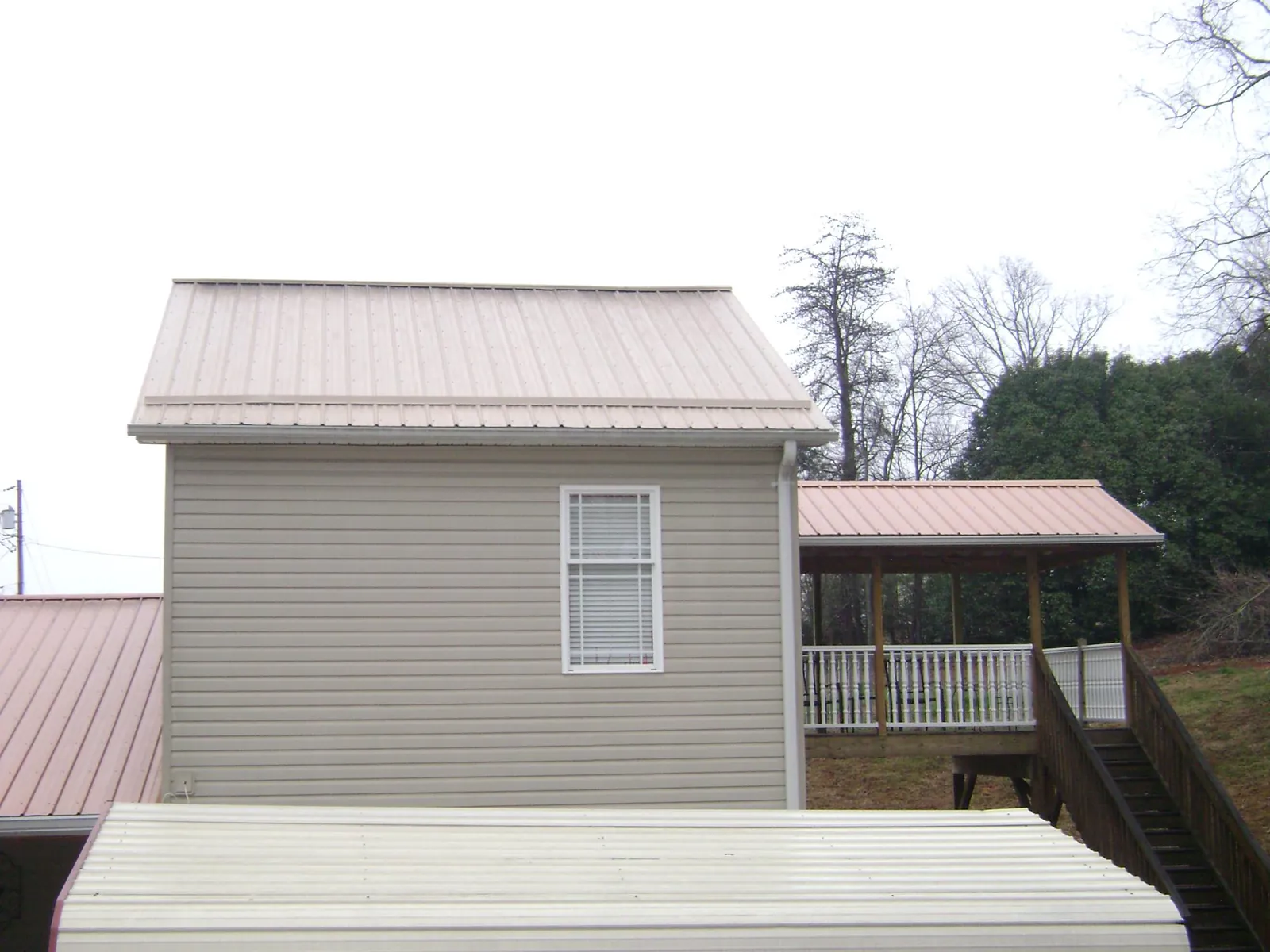 Tan metal roofs on a two story addition and attached porch, from a Roof Replacement job in Talbotton