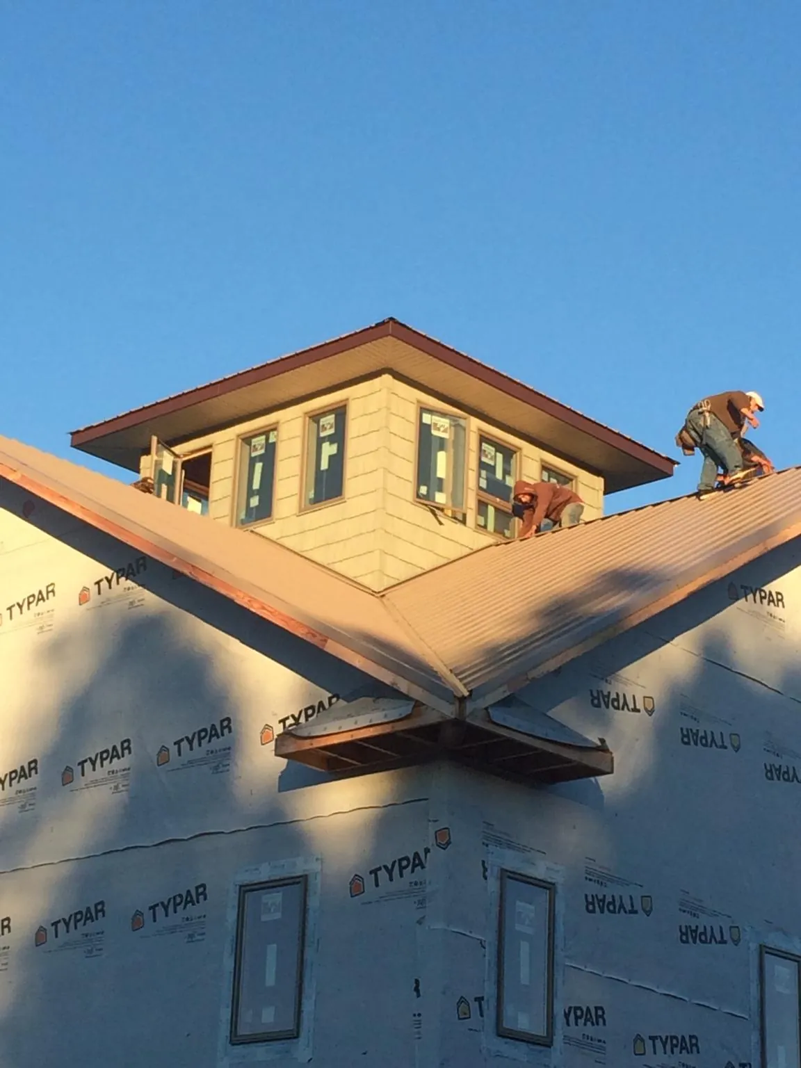 Roofers working around a rooftop cupola on a new metal roof at sunset — Roof Waterproofing in Talbotton by Roofing Brothers